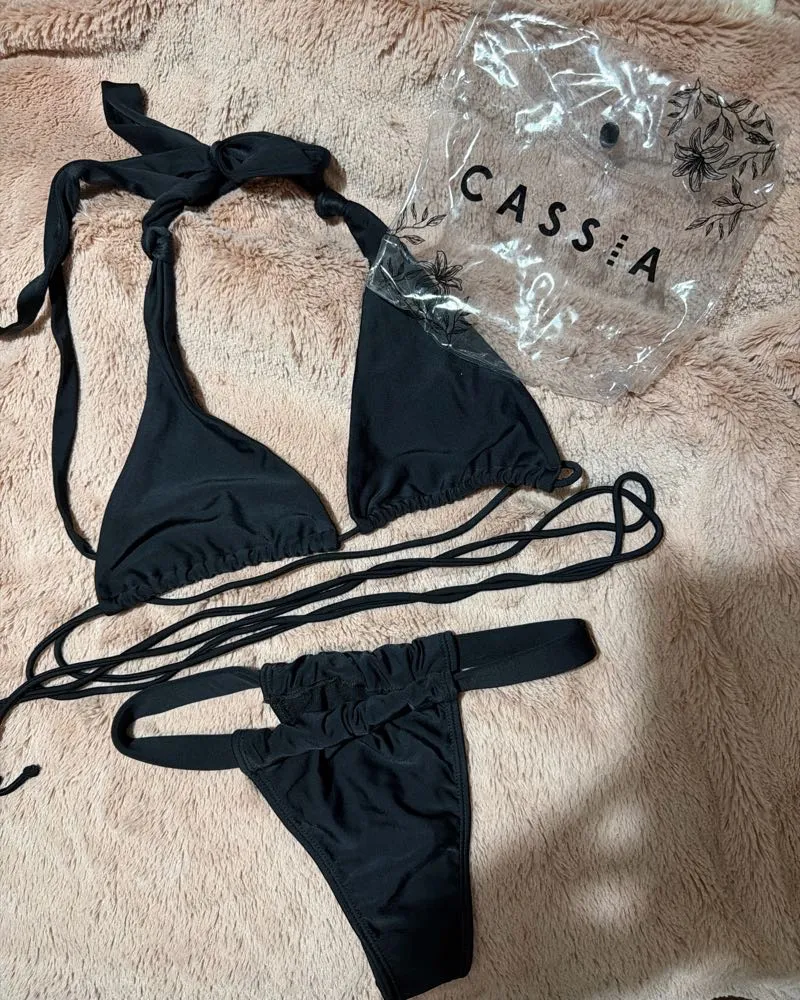 Bikini negra de dos piezas, con corpiño triangular y bombacha colaless. Ambas piezas son regulables mediante tiras para atar. Ideal para disfrutar del sol y el mar.