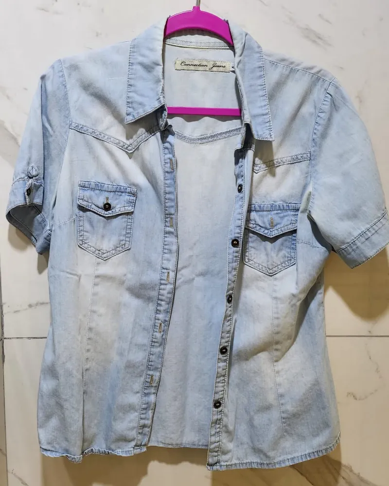 Camisa de jean de manga corta, con cuello, botones al frente y dos bolsillos en el pecho.