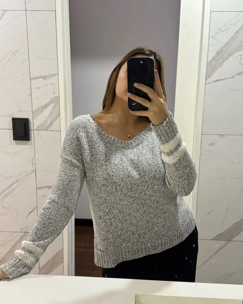 Sweater de tejido rústico en color gris melange con detalles a rayas en las mangas. Posee escote en V y un corte moderno.