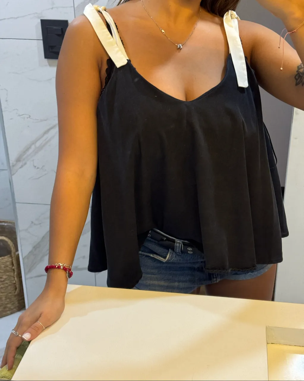 Musculosa negra con breteles blancos anudados en los hombros. Escote en V.