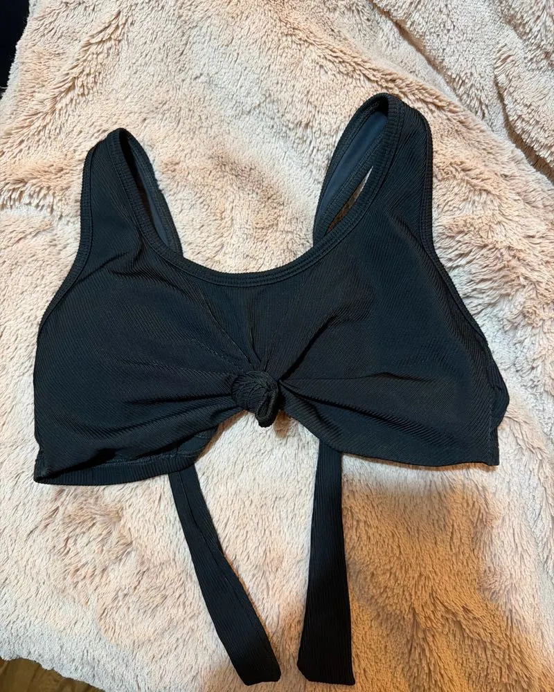Top de bikini negro con nudo al frente y tiras regulables. Ideal para lucir en la playa o piscina con mucho estilo.