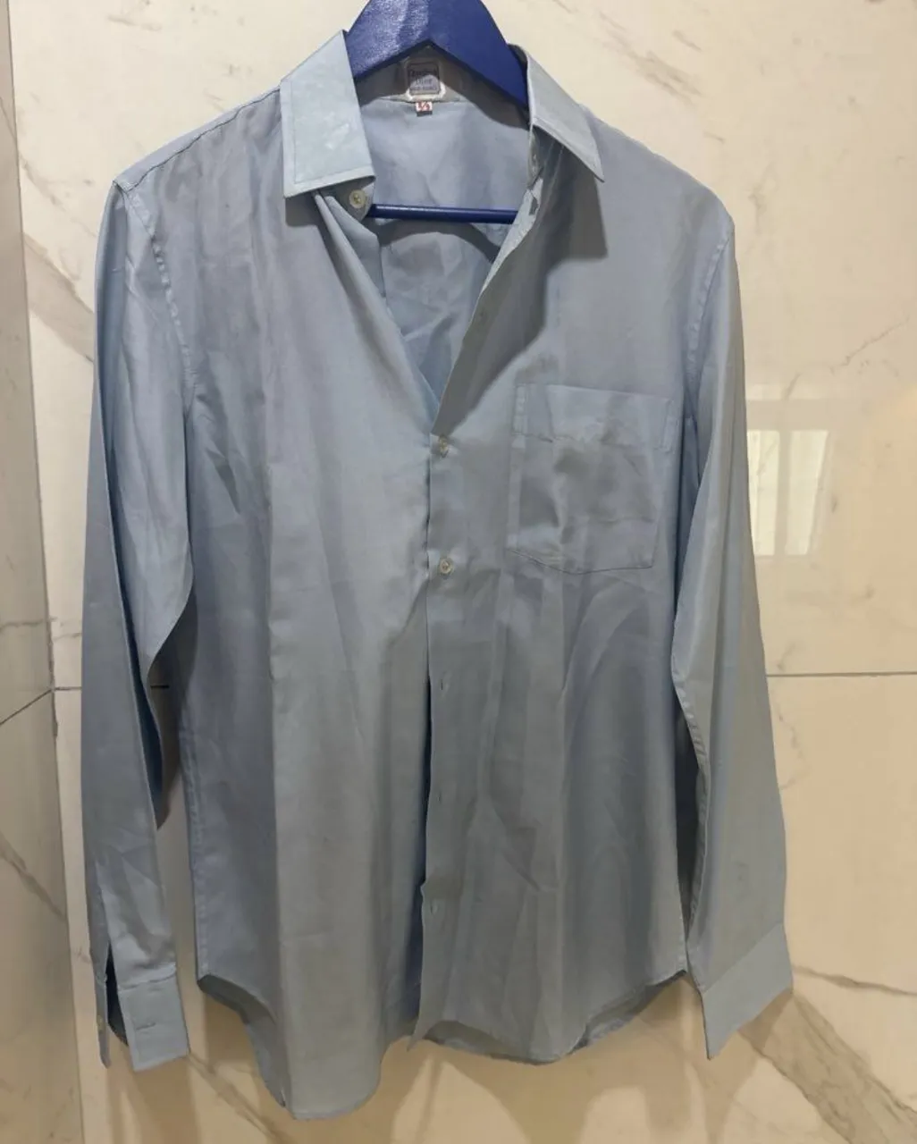 Camisa de vestir clásica de color celeste. Posee un bolsillo en el frente y cuello tradicional. Ideal para un look formal o casual.