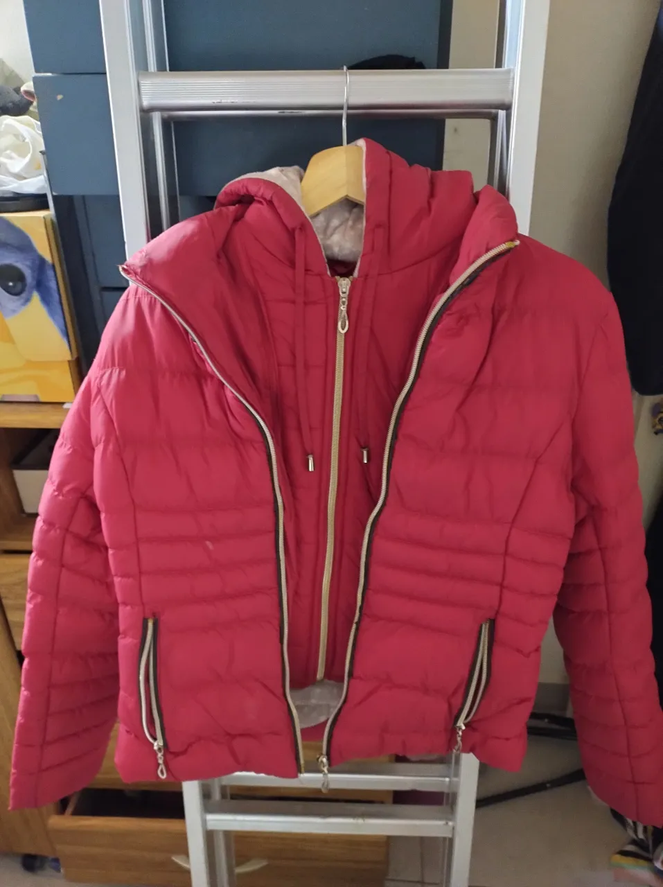 Campera acolchada roja con capucha, ideal para el frío. Tiene cierre al frente y bolsillos con cierre en los laterales. El interior de la capucha y la campera tiene un estampado sutil.
