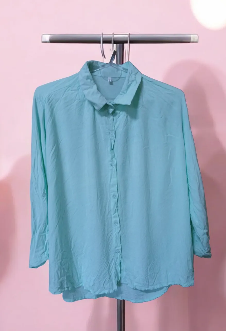 Camisa celeste de manga larga con botones al frente y cuello clásico.