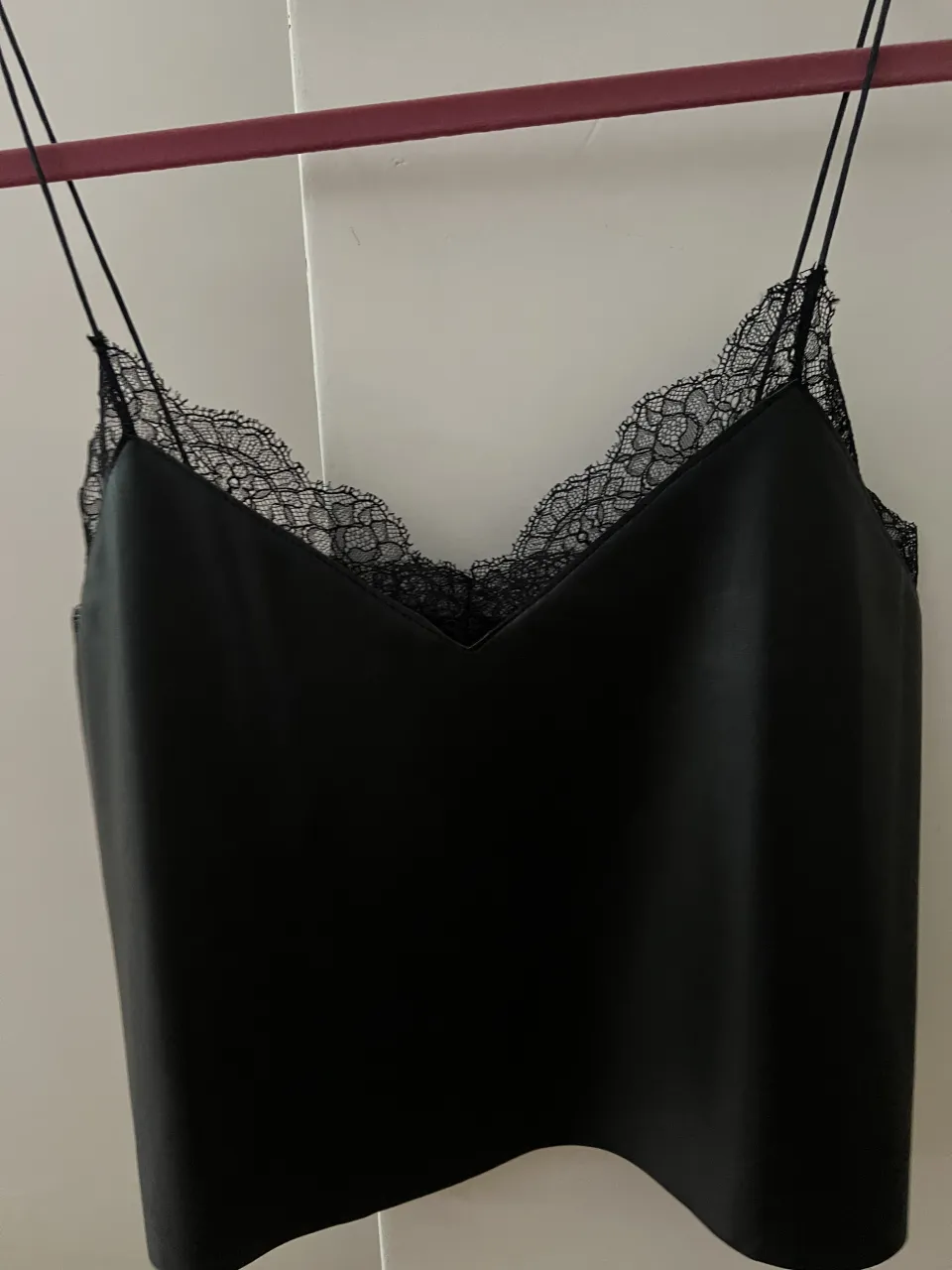 Top negro con breteles finos y detalles de encaje en el escote.