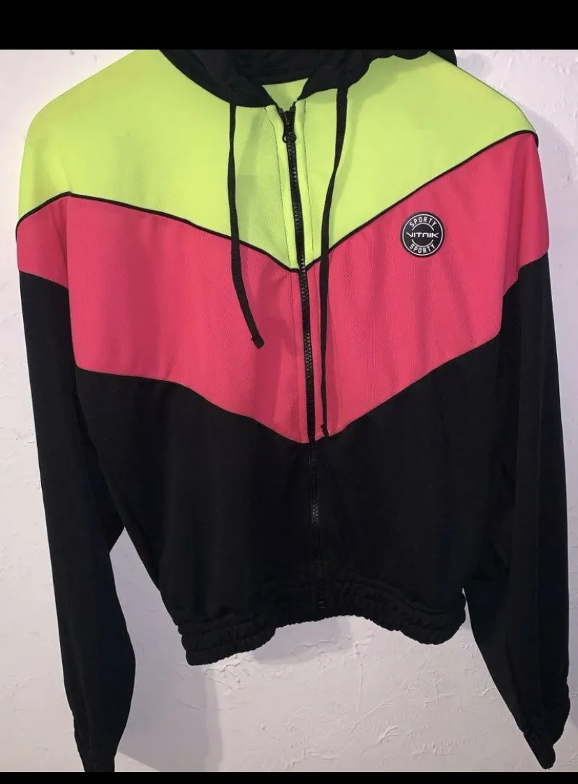 Buzo deportivo crop con capucha y cierre al frente. Diseño de bloques de color en verde lima, rosa y negro. Puños y cintura elastizados.