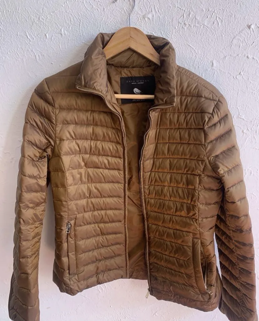 Campera acolchada marrón con cierre completo y cuello alto. Posee bolsillos laterales con cierre.