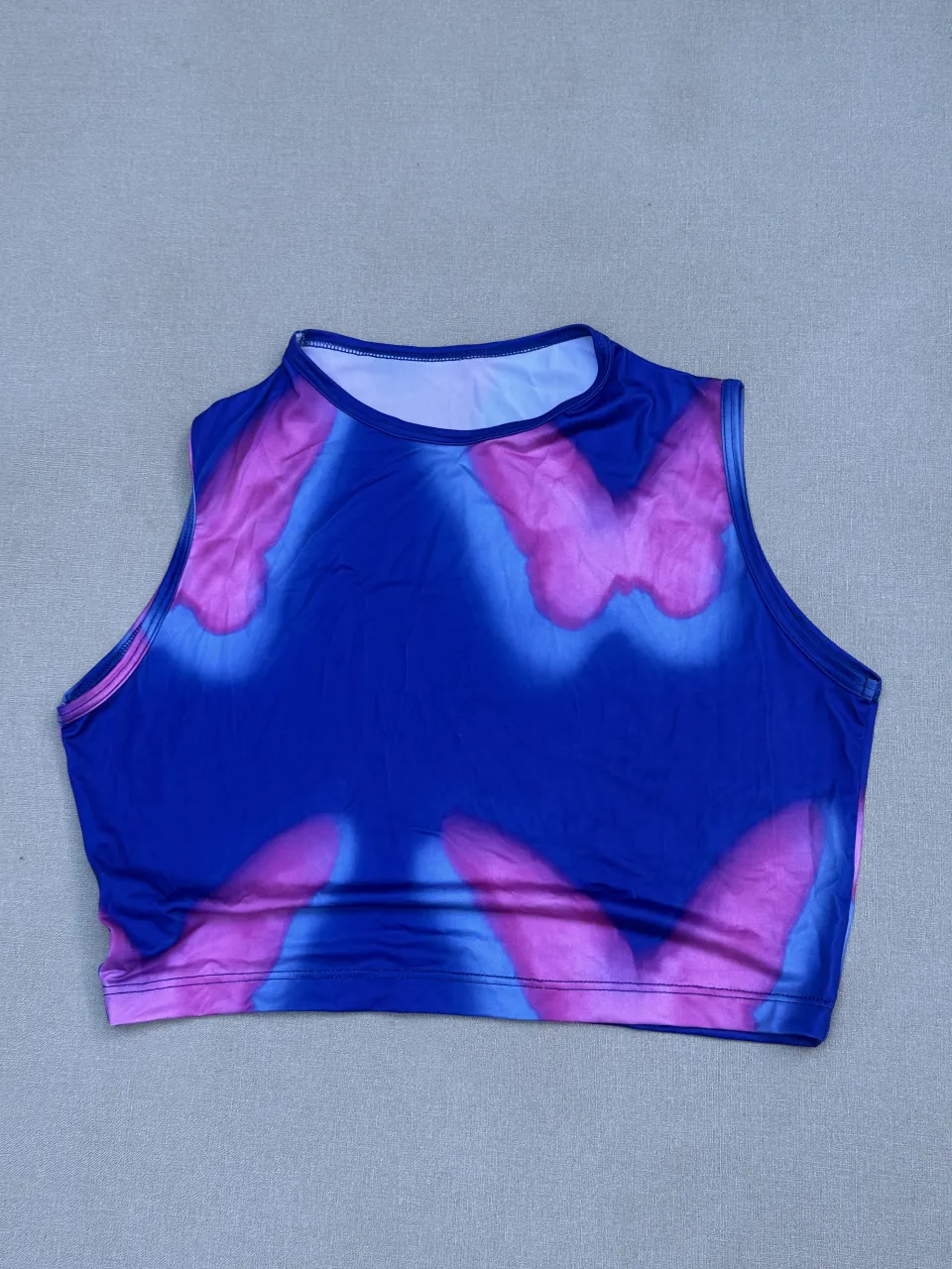 Top crop con estampa de mariposas en degradé de azul y rosa. Diseño moderno y llamativo, ideal para un look canchero y a la moda.