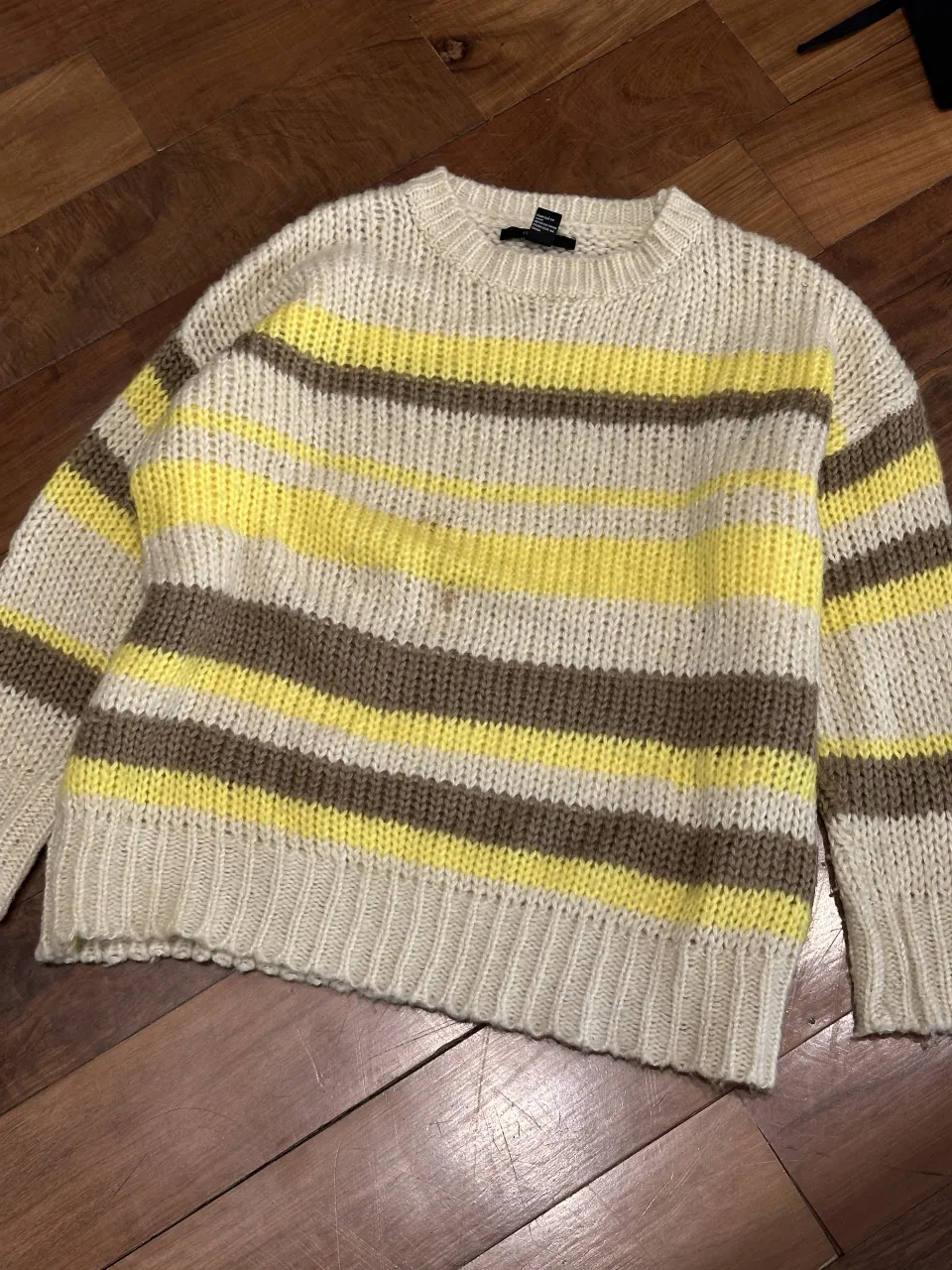 Sweater de tejido a rayas horizontales en tonos beige, marrón y amarillo. Cuello redondo y mangas largas.