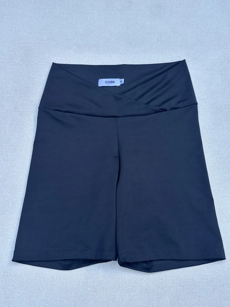 Shorts de lycra negros, tiro alto, con un diseño cruzado en la cintura que le da un toque moderno y canchero. Ideales para entrenar o para un look deportivo casual.