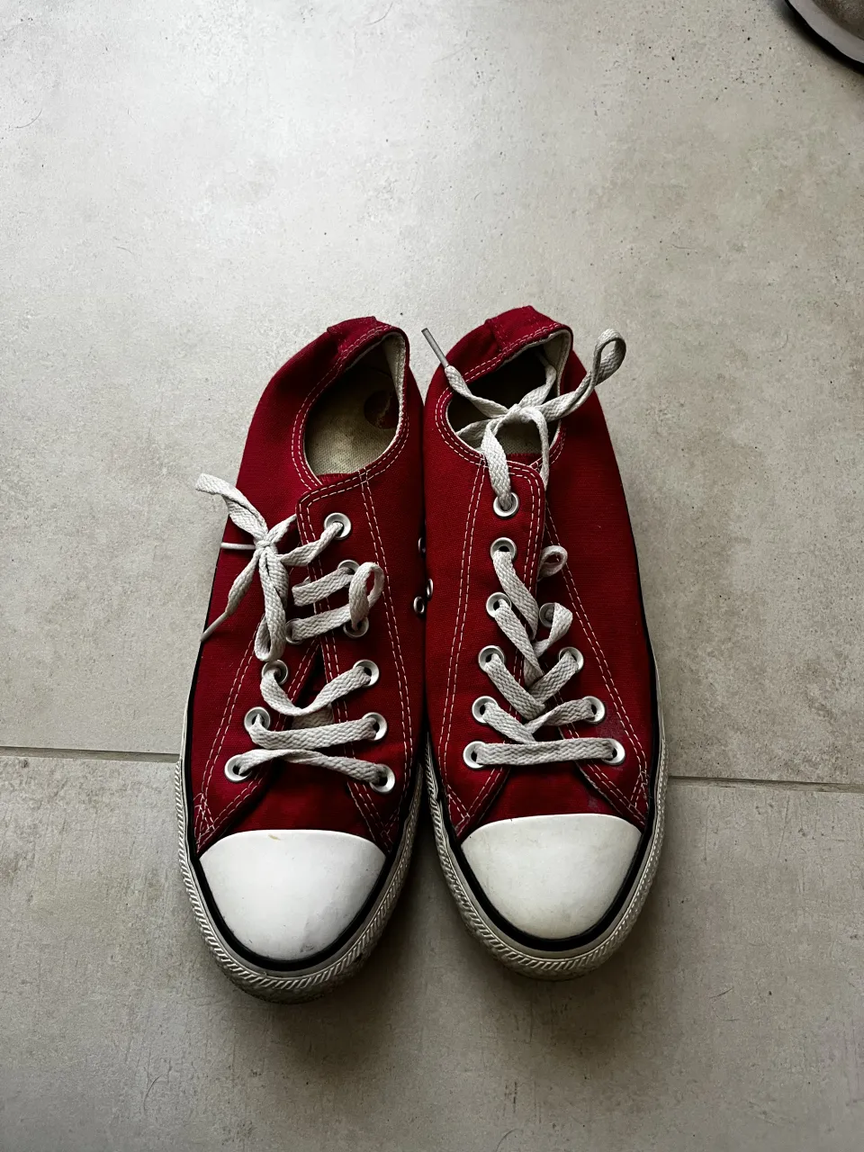 Zapatillas de lona color rojo con cordones blancos. Punta reforzada de goma blanca y suela de goma blanca con detalles en negro.