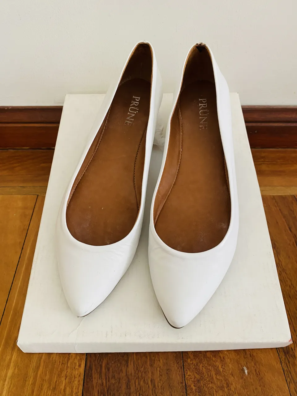 Chatas PRUNE blancas de cuero, con suela de goma y detalle metálico dorado en el talón con gravado de la marca.
Elegantes. Impecables, un solo uso.