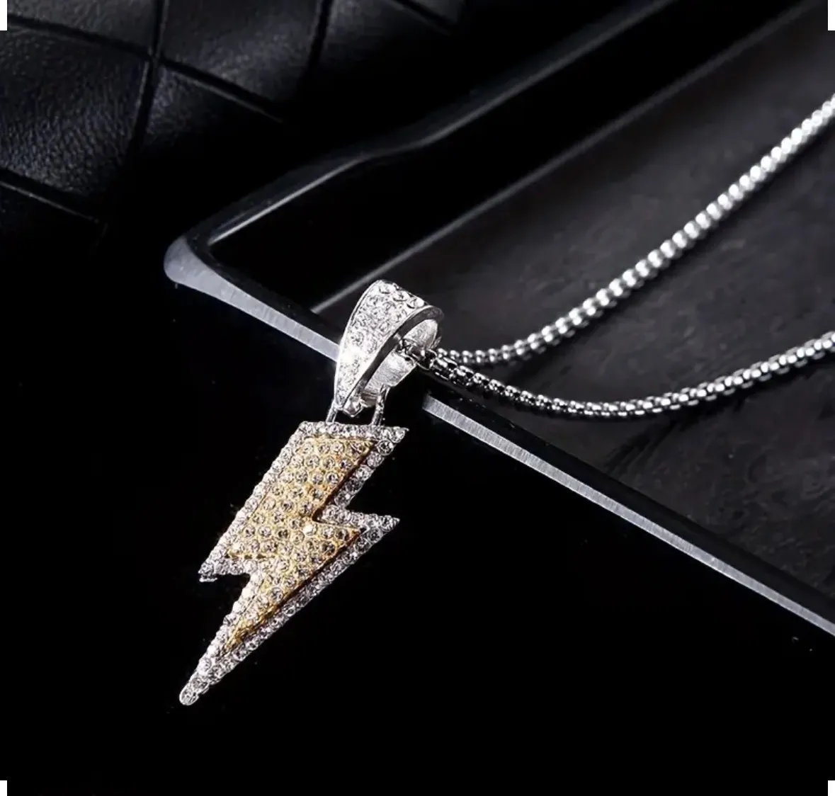 Cadena plateada con dije de rayo con detalles en dorado y pedrería.