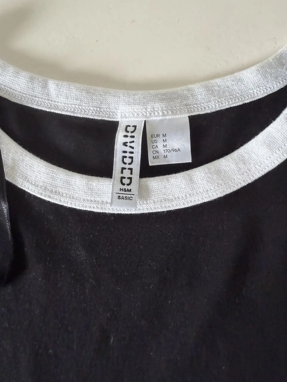 Remera negra básica con cuello y mangas en blanco. Ideal para el día a día, súper cómoda y versátil.