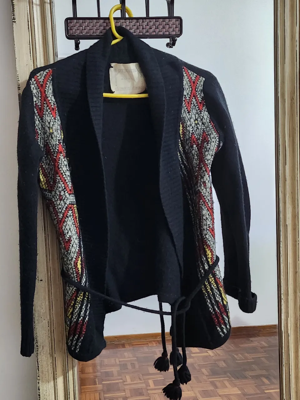 Cardigan negro con detalles de tejido en los laterales, con cinturón y flecos. Ideal para un look boho o casual.