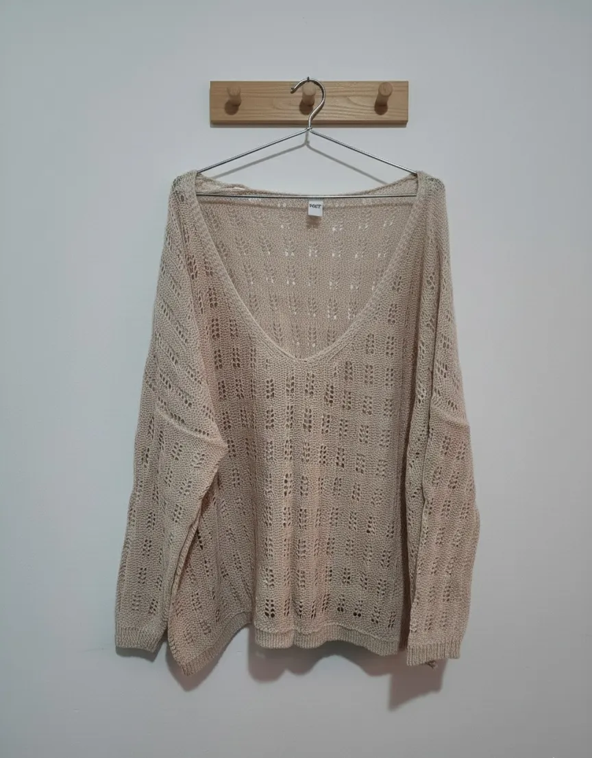 Sweater tejido de hilo color tiza, con escote en V pronunciado y detalles de rombos calados en toda la prenda. Mangas largas y corte holgado.