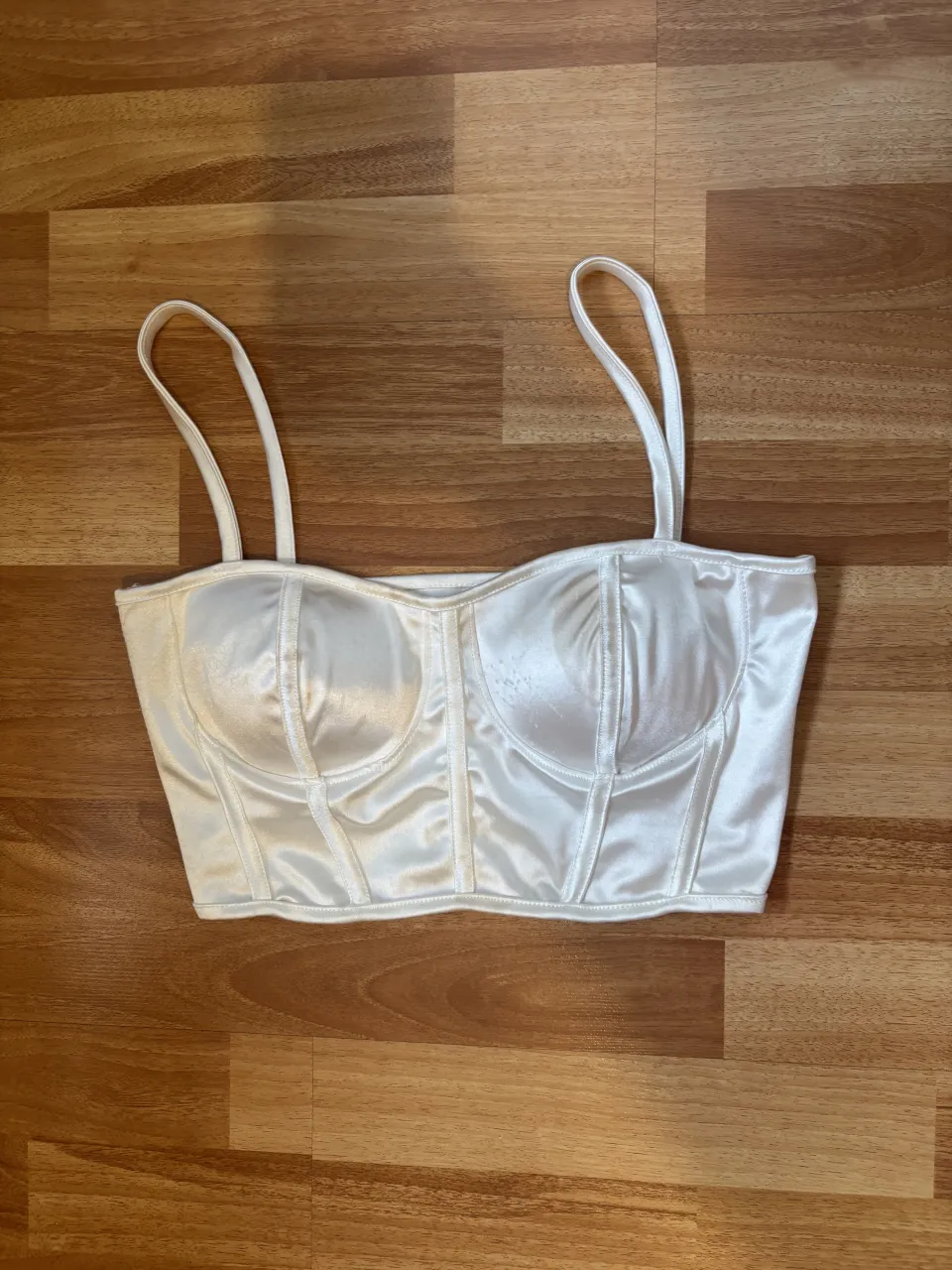 Top blanco con tiras finas y escote curvo. Posee tazas en la parte delantera para dar estructura.