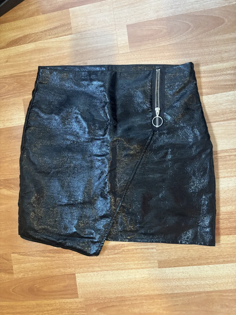 Pollera negra corta con detalle de cierre metálico y solapa asimétrica.