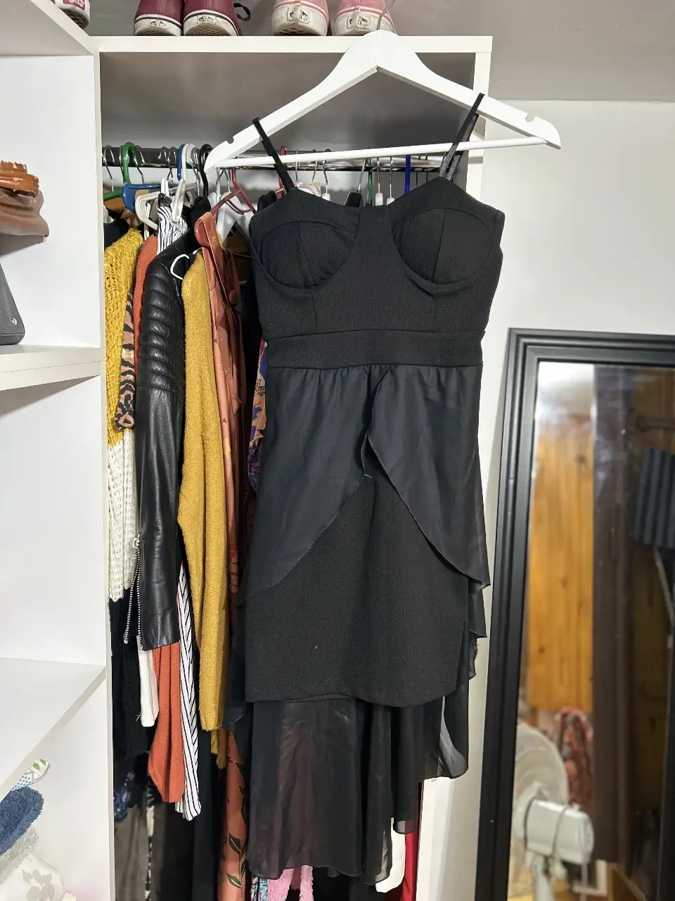 Vestido negro mini con detalles estructurados en la parte superior y falda con volados. Ideal para fiestas y eventos.