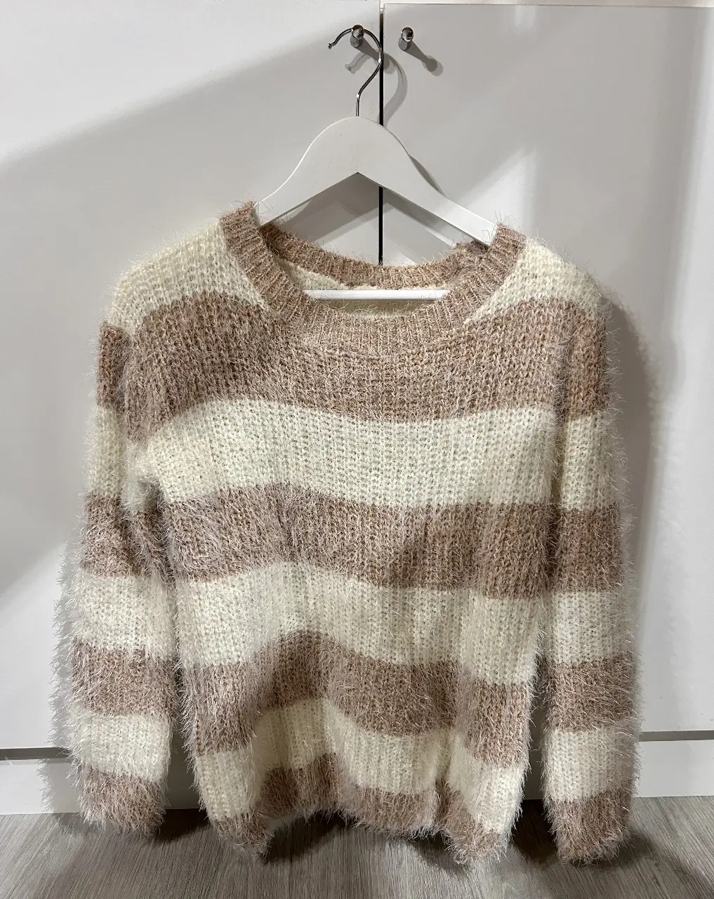 Sweater de mujer a rayas horizontales en color blanco y marrón. Tejido suave y abrigado, ideal para el invierno. Cuello redondo y mangas largas.