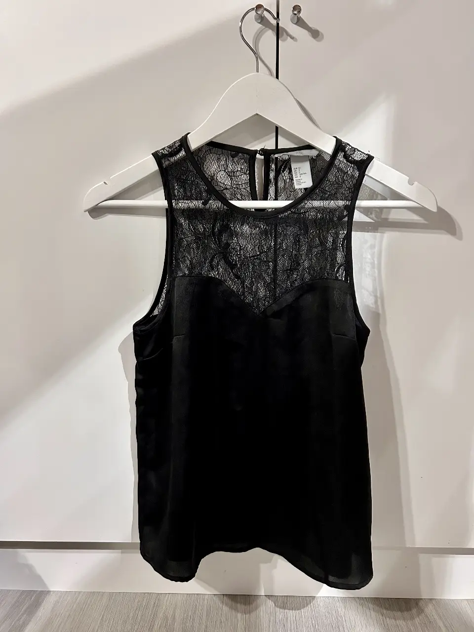 Blusa negra con detalle de encaje en la parte superior. Ideal para una salida o evento especial. Diseño elegante y femenino.