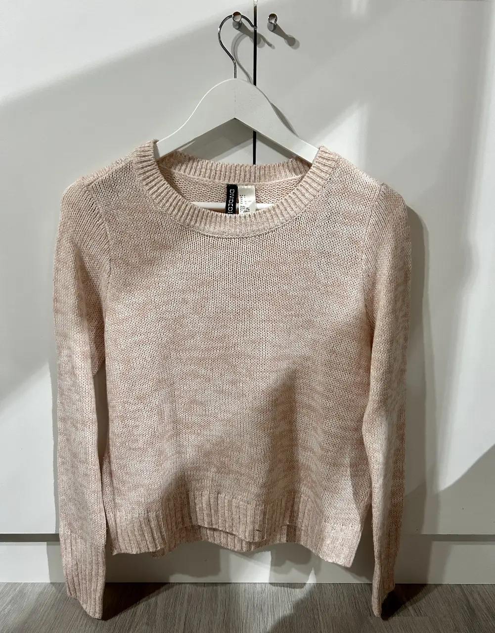Sweater de punto en color rosa claro, ideal para un look casual y cómodo. Perfecto para combinar con jeans o pantalones de vestir.