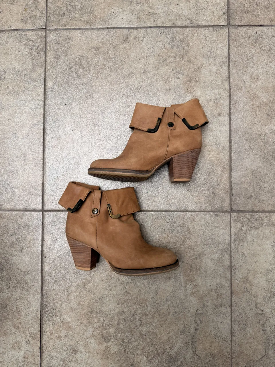 Botitas de cuero color suela con doblez en la parte superior y detalle de hebilla metálica.