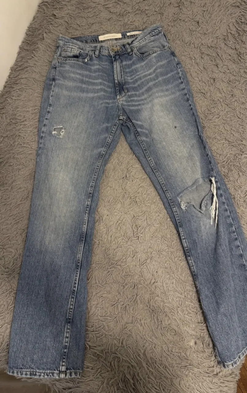 Jeans de tiro alto con roturas y desgastes. Presentan detalles de costura y bolsillos traseros con bordado. pequeña manchita en la pierna 