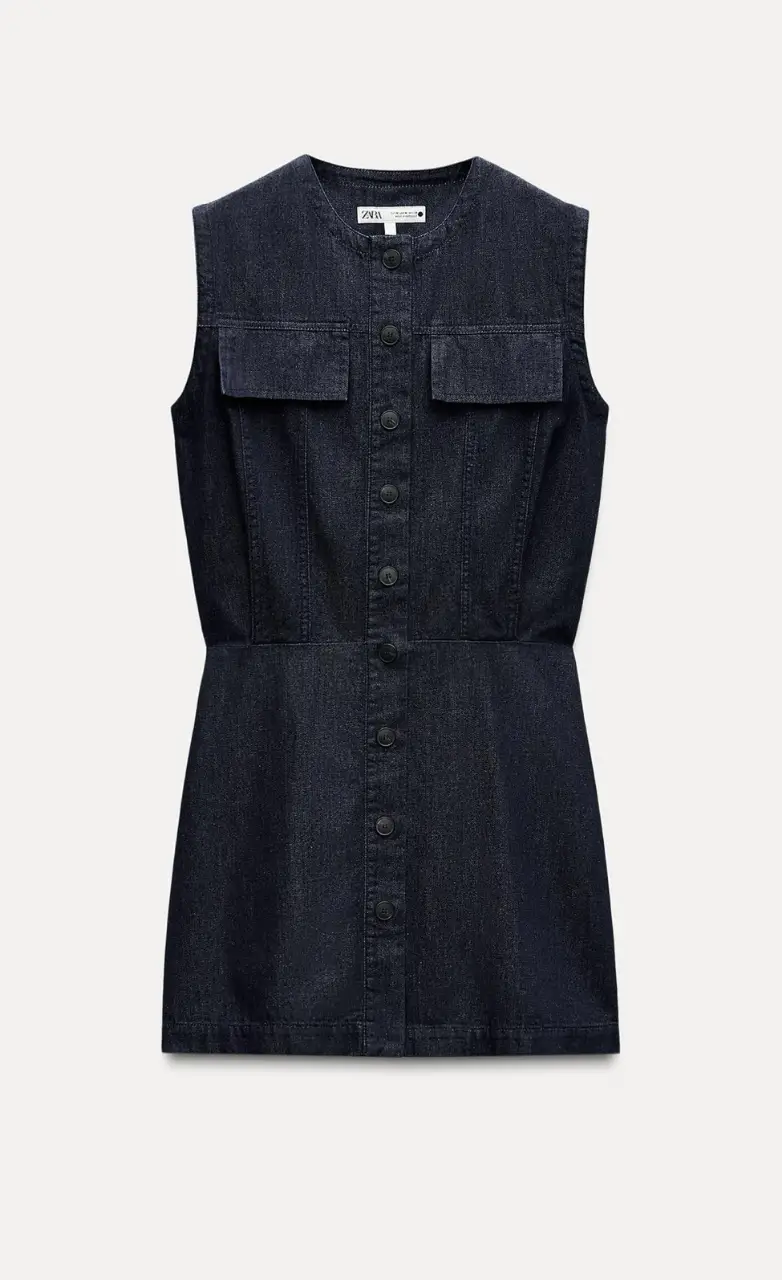 Vestido mini de jean azul oscuro, sin mangas, con botones delanteros y bolsillos en el pecho. Ideal para un look casual y moderno.