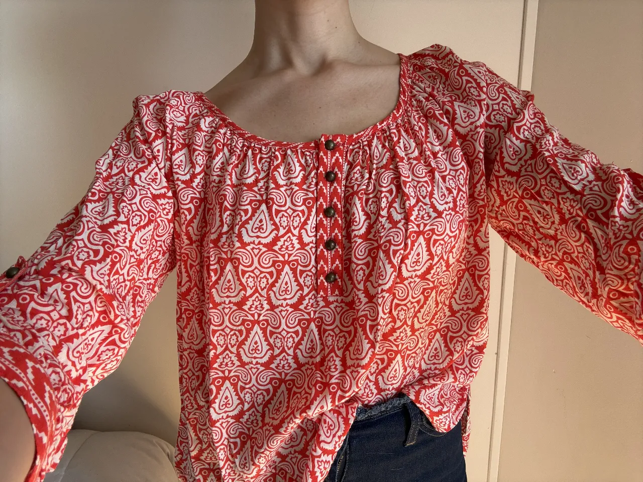 Blusa de mujer con estampado paisley en rojo y blanco. Tiene mangas 3/4 con botones en los puños y botones en la parte delantera. Ideal para un look casual y cómodo.