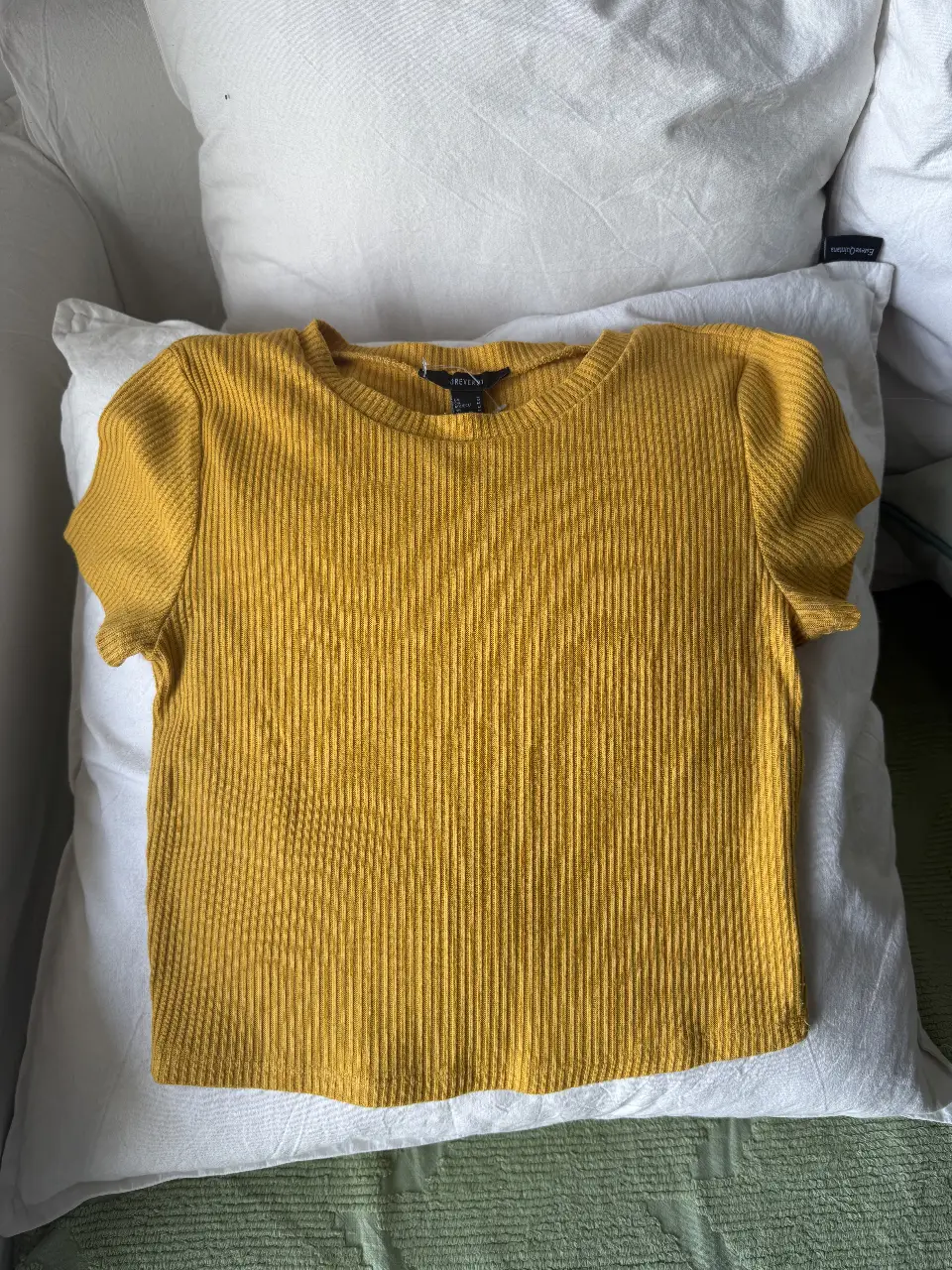Remera de mujer de color amarillo mostaza, de tejido acanalado. Cuello redondo y mangas cortas. Ideal para un look casual y cómodo.