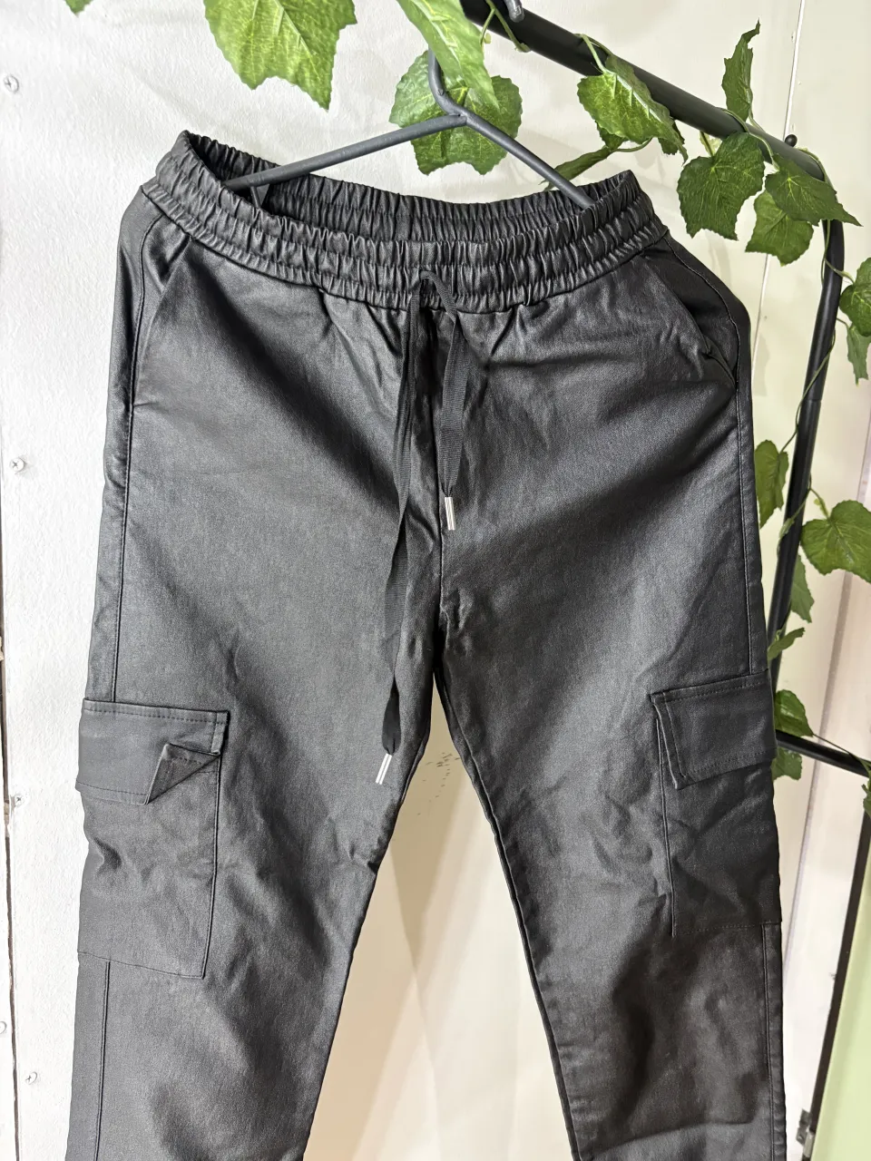 Pantalón cargo de cuero sintético negro, con cintura elastizada y cordón ajustable. Posee bolsillos cargo con solapa en los laterales.