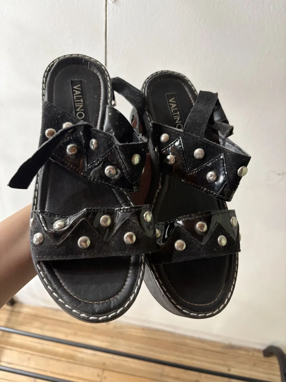 Sandalias negras con tachas plateadas y plataforma. Tienen tiras anchas y detalle de charol.breve rayadura en la parte del taco