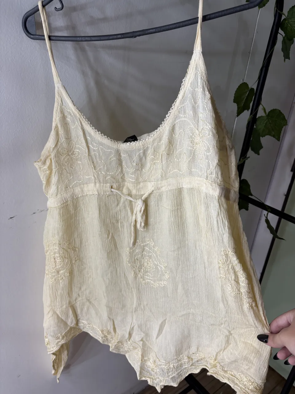 Top de seda color crema con bordados florales y detalles de encaje. Posee tiras finas y un lazo ajustable en la cintura. Ideal para un look boho chic o romántico.alguna q otra manchita