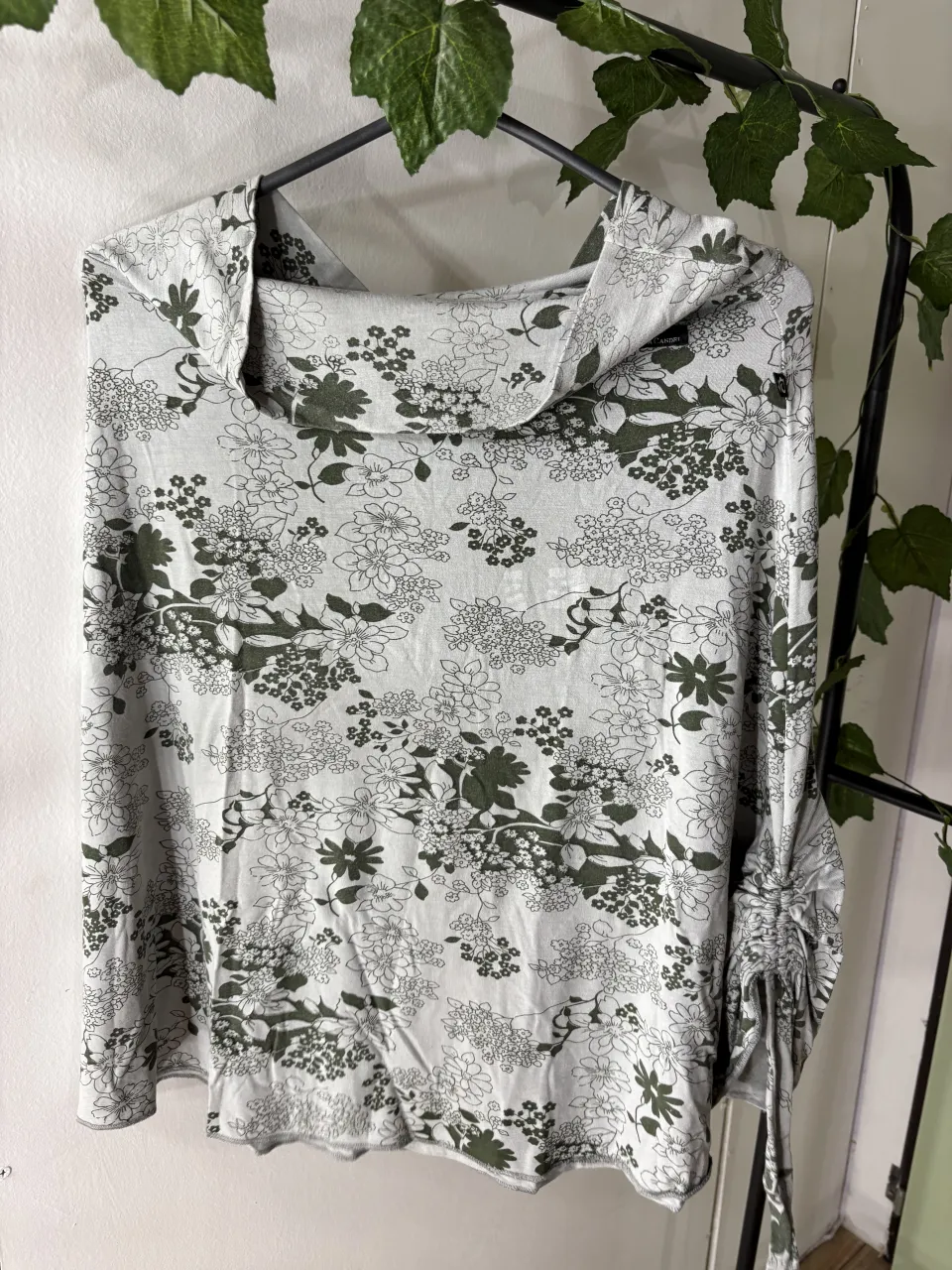Remera manga larga con cuello polera y estampa floral en tonos verdes y blancos. Detalle de fruncido en las mangas.