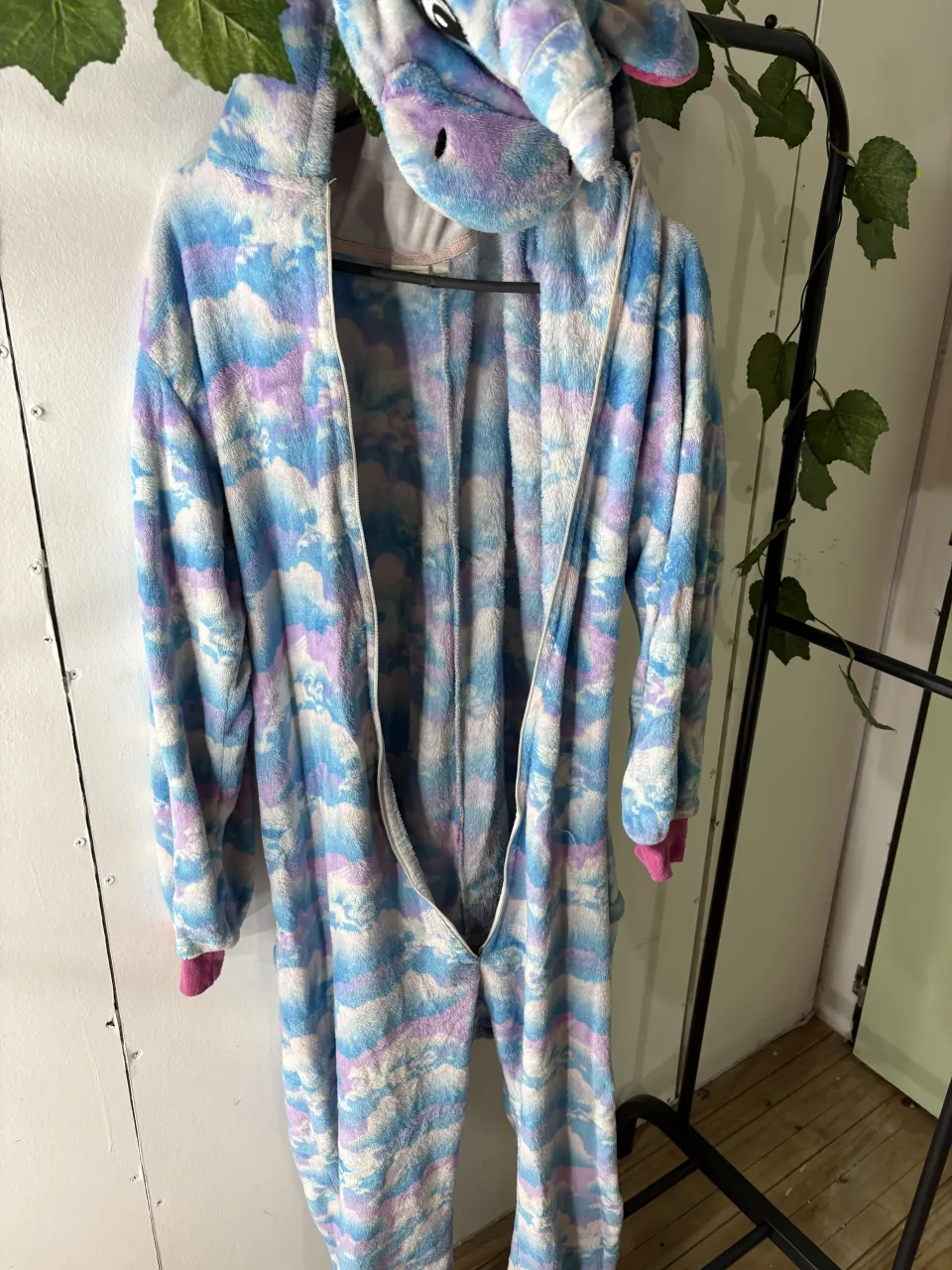 Mono de unicornio súper tierno y cómodo, ideal para estar en casa o para una fiesta de disfraces. Tiene un estampado de nubes celestes y lilas, con capucha y cierre al frente. ¡Perfecto para sentirte mágico! breve rotura, leves manchas y falta de cierre
