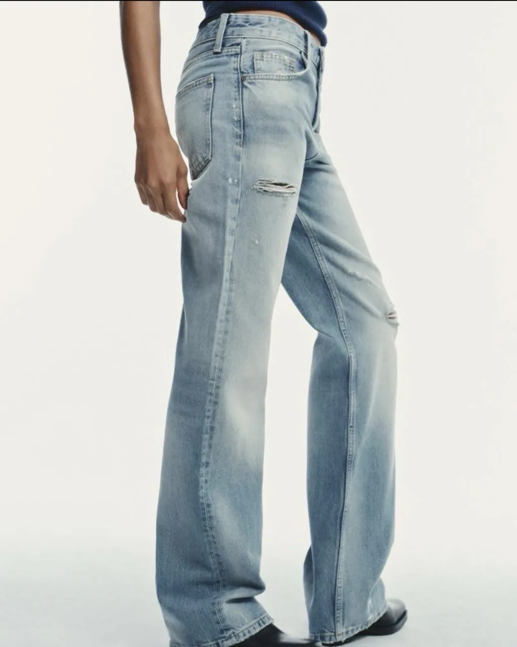 Jean de tiro alto con roturas y efecto desgastado. Modelo ancho en las piernas.