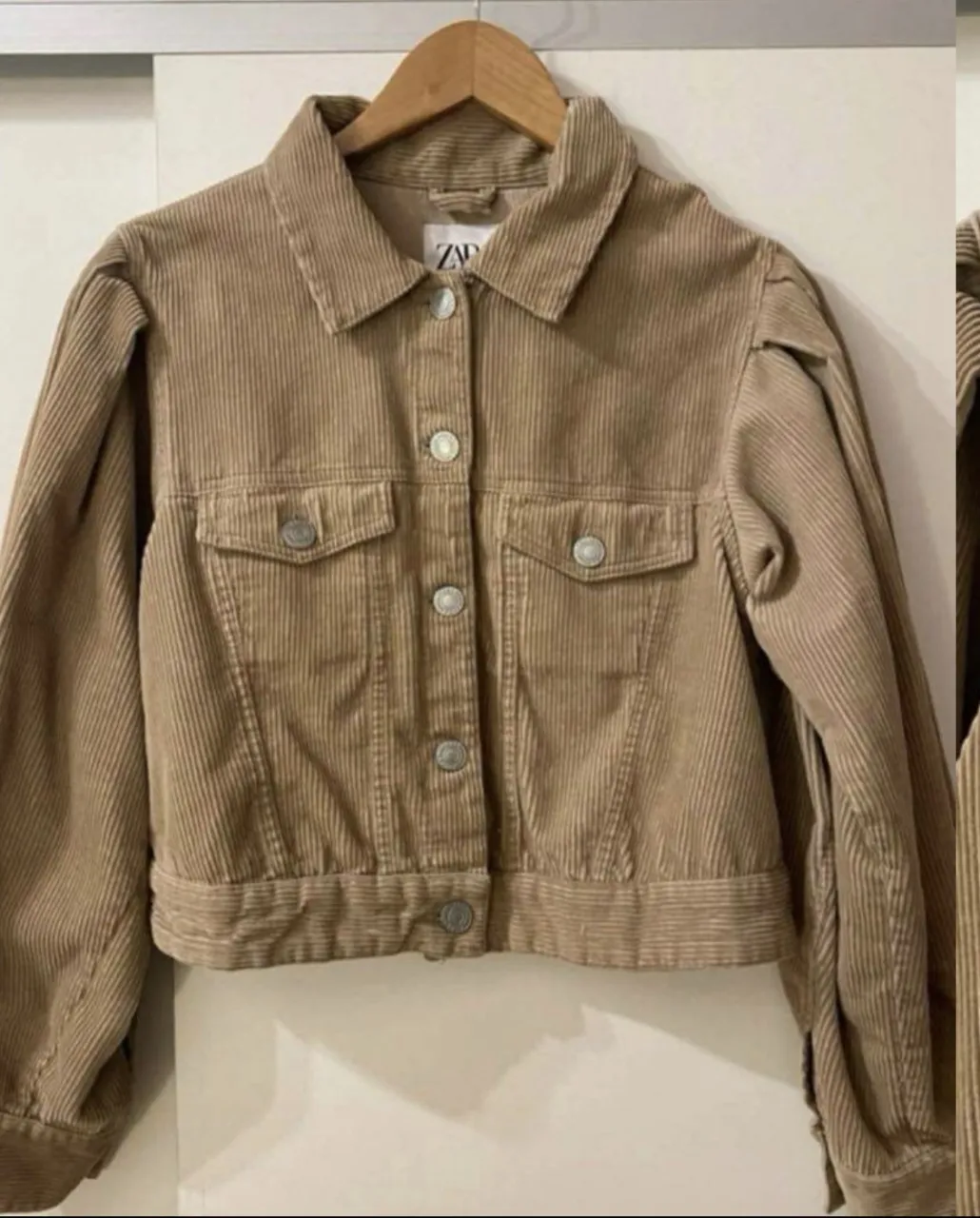 Campera de pana color marrón con botones al frente y en los bolsillos. Mangas largas con puños y detalle de fruncido en los hombros.