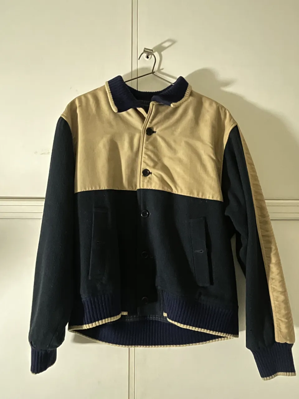 Campera estilo universitario con cuello y puños de ribb azul marino. Cuerpo de la campera en color azul marino y mangas en color beige. Cierre de botones a presión.