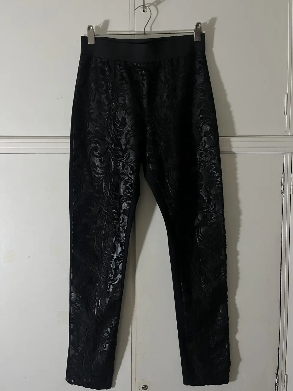 Pantalón negro con diseño floral en relieve y cintura elastizada.