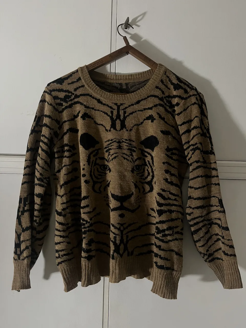 Sweater de lana tejido con estampa de tigre en el frente y en las mangas. Posee cuello redondo y puños tejidos.