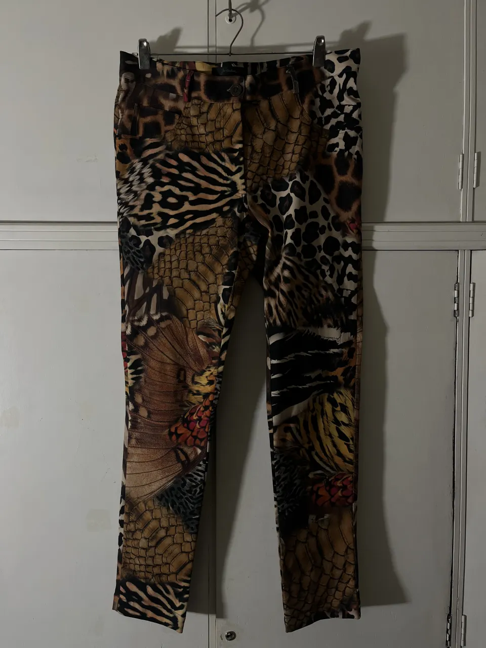 Pantalón estampado con motivos de animales y plumas. Posee bolsillos delanteros y cierre con botón.