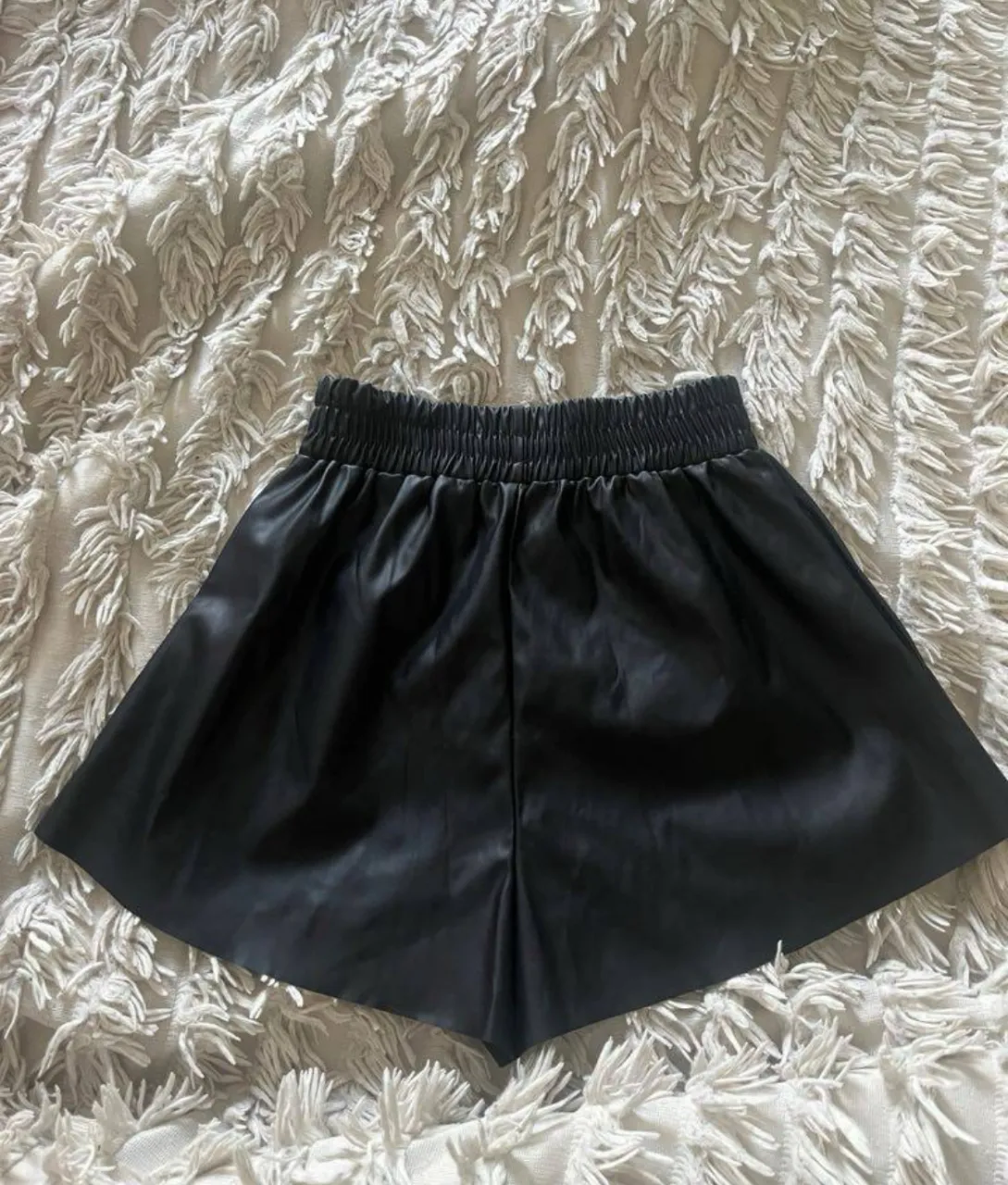 Shorts negros de cuero sintético con cintura elastizada.