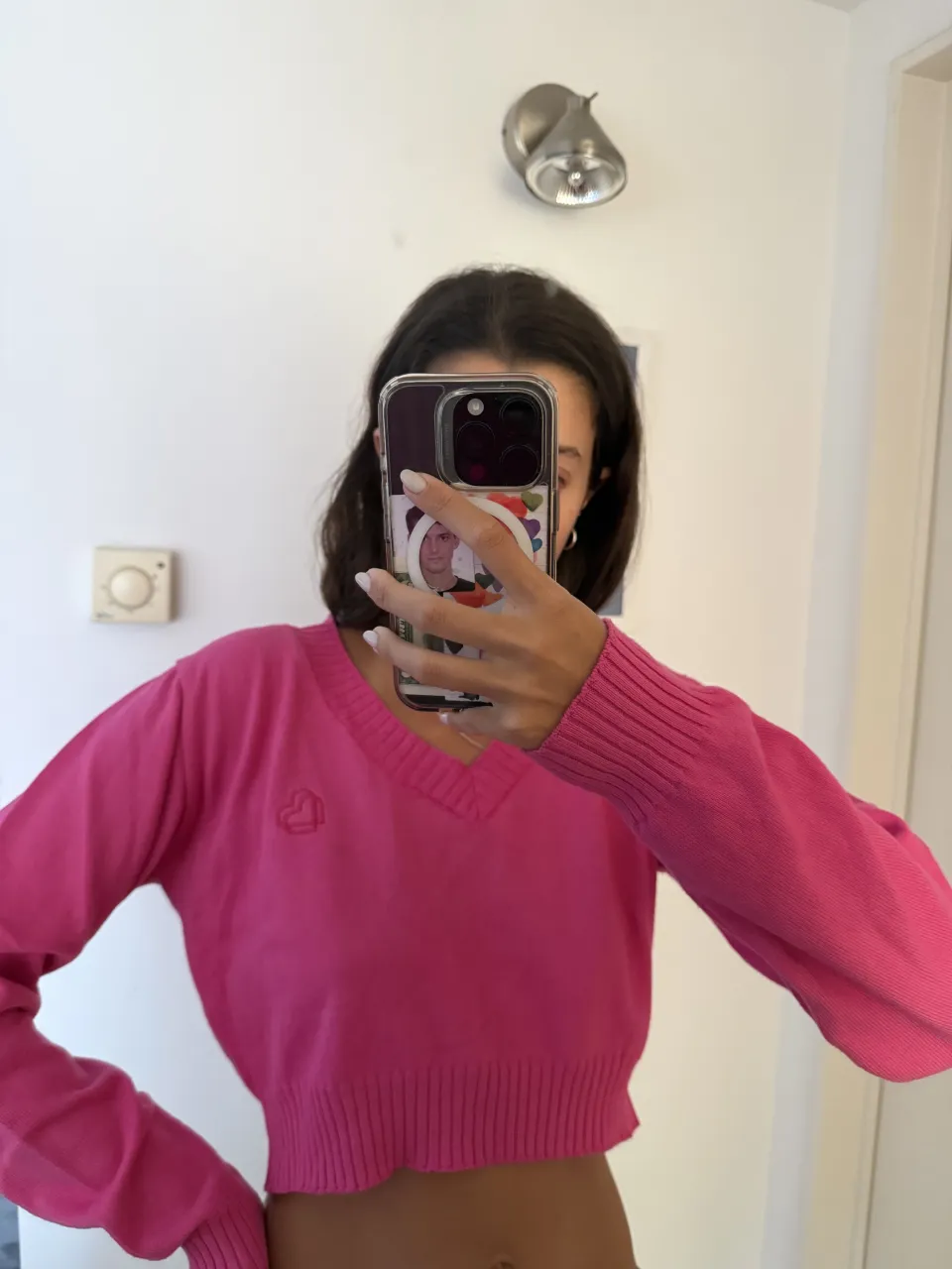 Sweater rosa escote en V con puños y cintura tejidos. Pequeño corazón bordado en el frente.