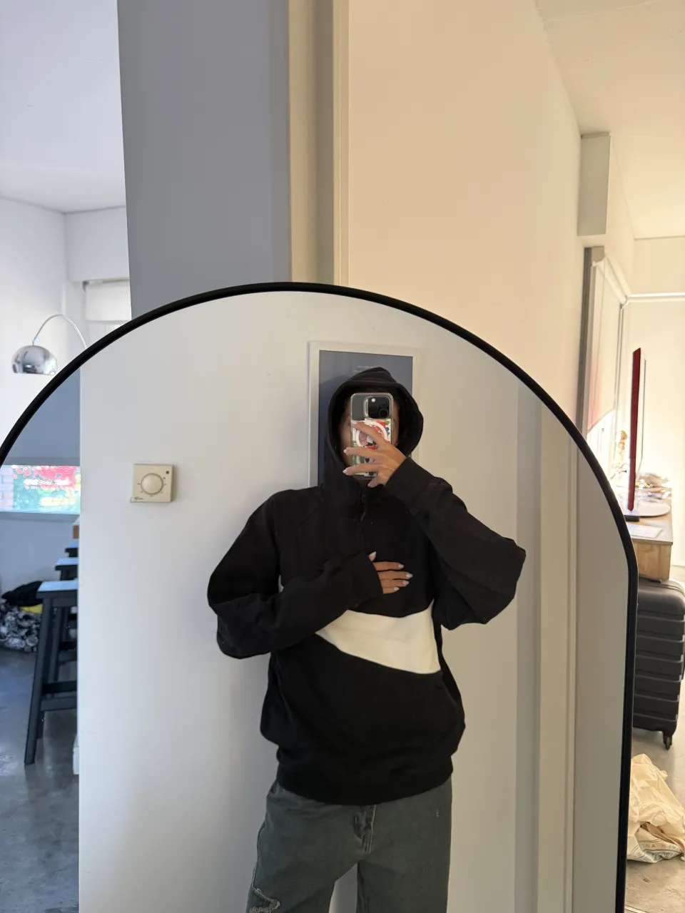 Buzo negro con cierre de un cuarto y logo grande blanco en el frente.