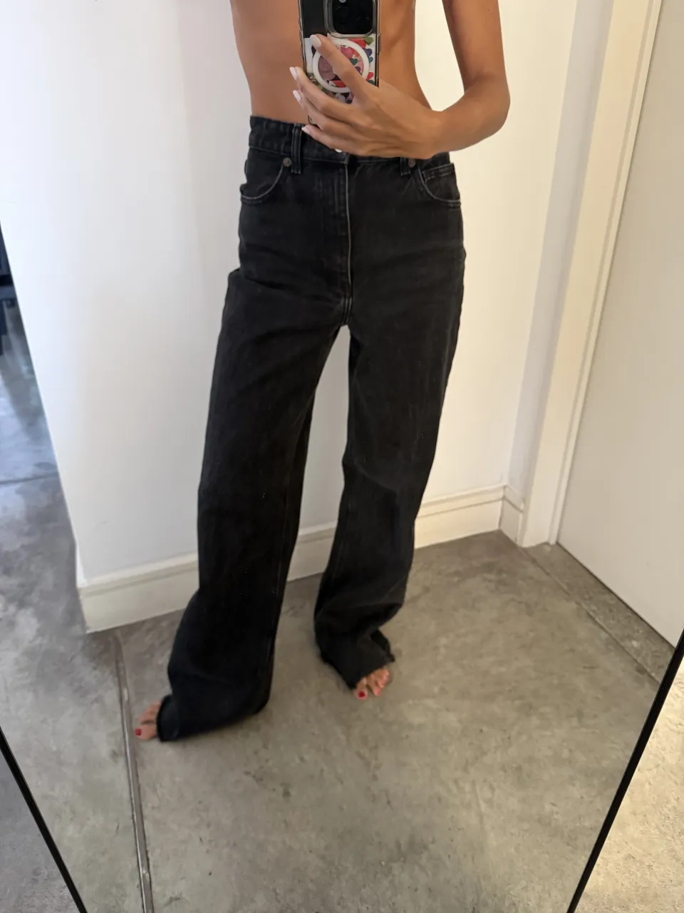 Jeans negros de tiro alto con roturas en los tobillos.