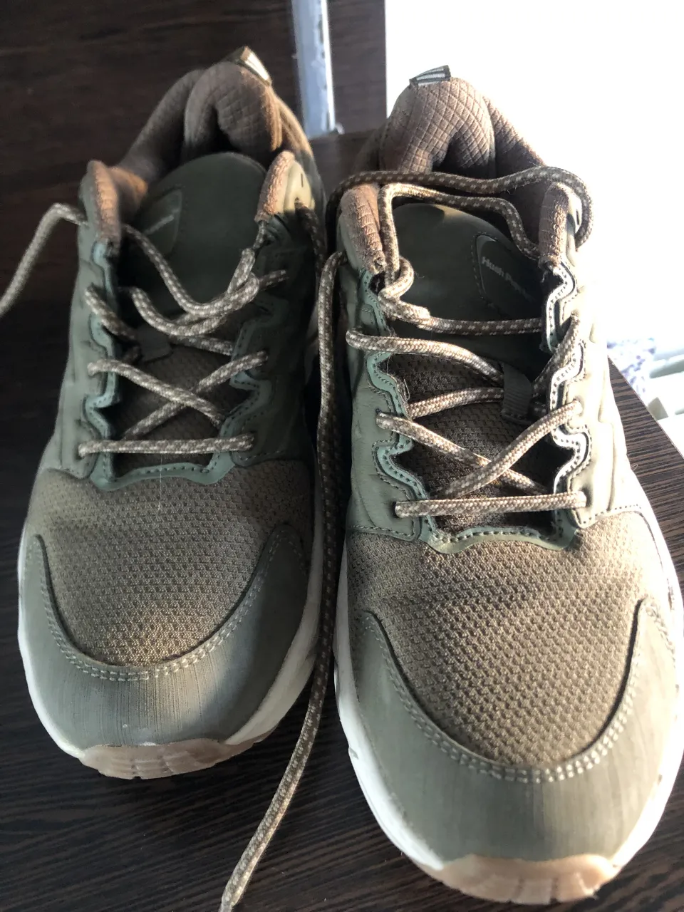 Zapatillas deportivas color verde militar con cordones y suela blanca. Detalle de la marca 'HUSH' en el lateral.