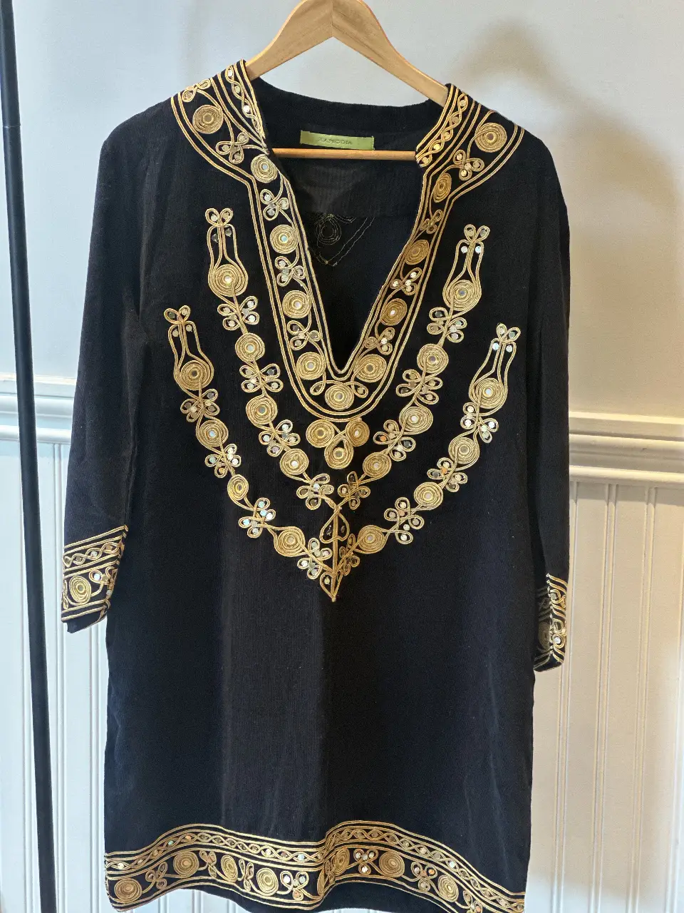 Vestido largo negro con detalles dorados bordados. Cuello en V y detalles en mangas y bajo. Ideal para eventos especiales o fiestas.