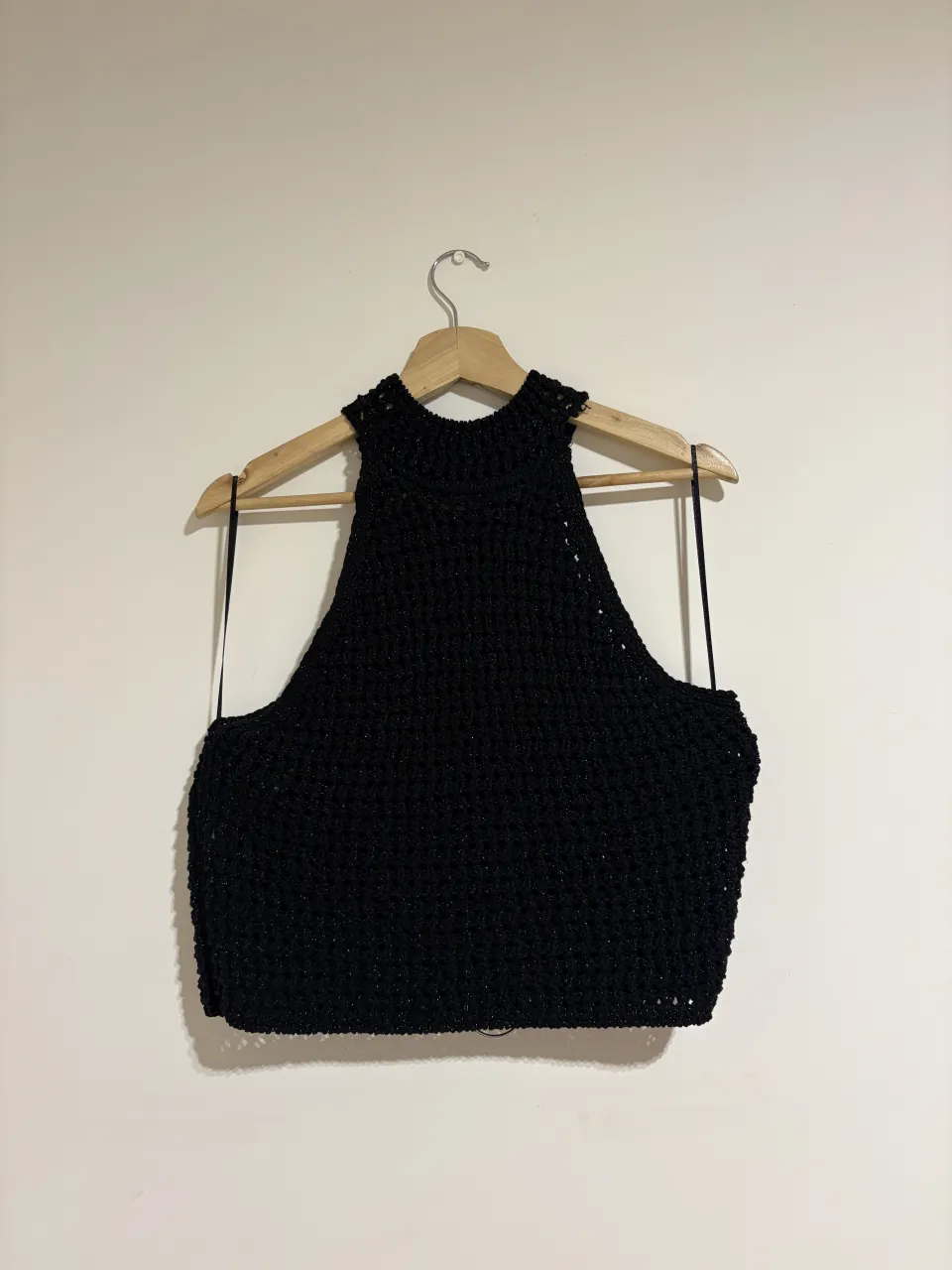 Top negro tejido con cuello alto y tiras finas en la espalda.