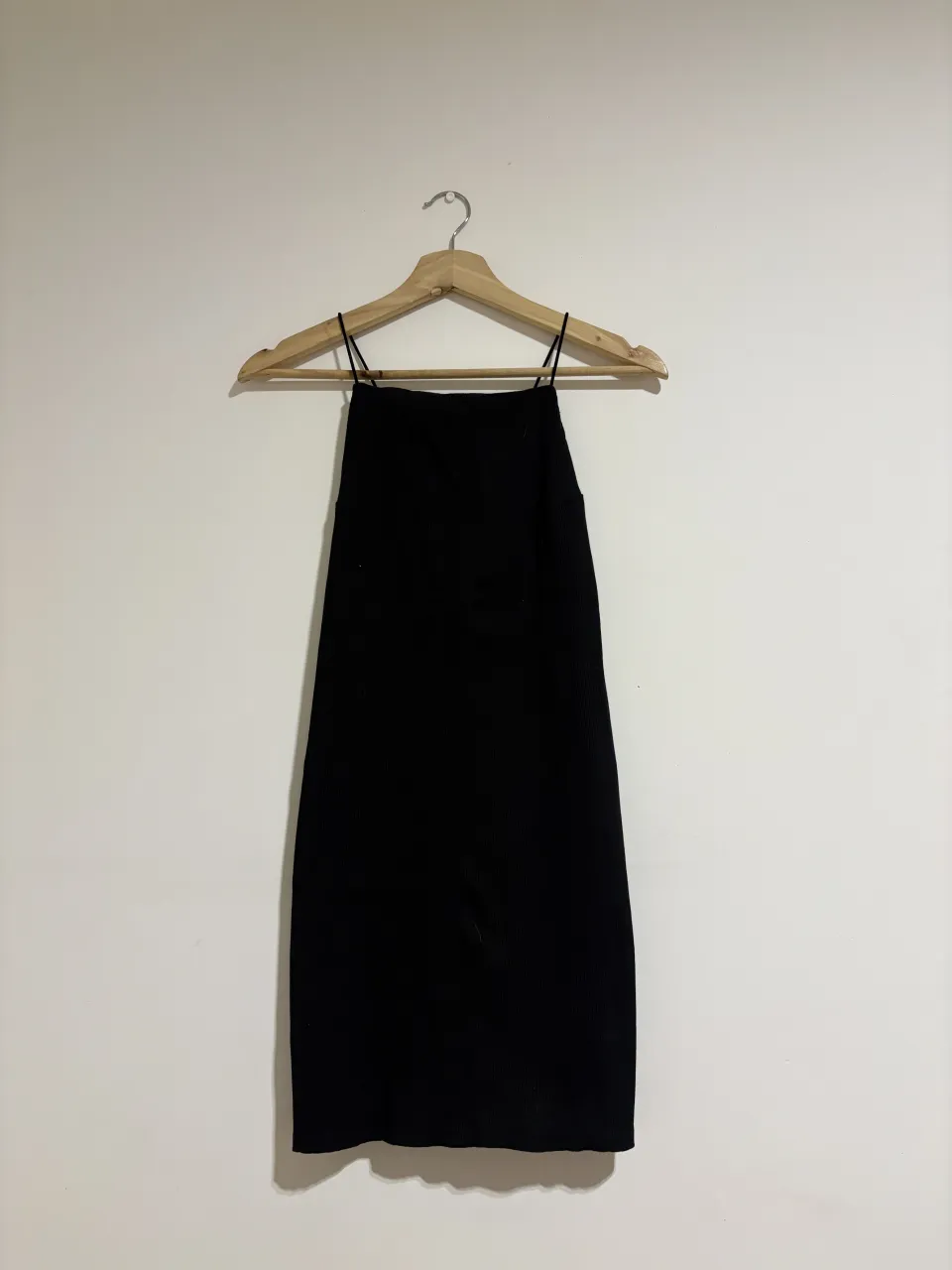 Vestido negro con tiras finas y escote cuadrado. La espalda tiene un diseño cruzado con tiras.